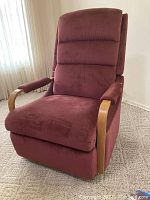 Front view of La-Z-Boy rocker recliner with raspberry colored fabric upholstery and wooden armrests, placed on a carpeted floor.