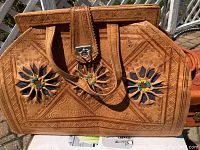 Front view showing floral embossed leather motifs with colorful bead accents and metal latch.