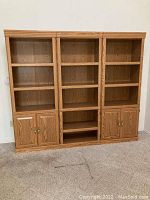 Front view of assembled three-piece oak-look wall unit showing open shelving and lower cabinets