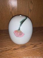 Front view of the pottery vessel showing pink flower with green stem design on white background