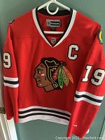 Front view of red women's Chicago Blackhawks hockey jersey with Jonathan Toews number 19, captain's 'C', and team logo.