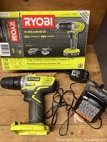 Full drill kit displayed outside original box showing drill, battery and charger with cords on wooden surface.