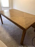Photo showing the rectangular dining table top with geometric wood grain pattern and square legs visible