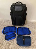 Four blue breathable packing bags of various sizes laid out flat in front of the suitcase.