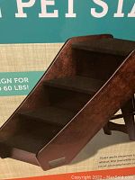 Close view of the wooden pet stairs showing dark brown wood and fabric steps.