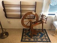 Wide view showing wooden wall shelf mounted on wall, spinning wheel on small rug below