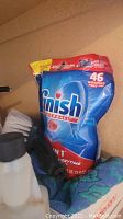 Red and blue Finish Powerball dishwasher detergent bag with 46 packs and some black hose pieces visible on the side