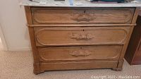 Front view of the dresser showing three drawers with ornate carved wooden trim and oak finish.