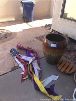 First photo showing large glazed pot, windsocks laid out on ground, and wooden plant stand wheels visible