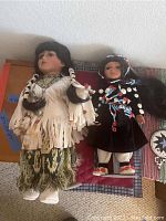 Two Native American dolls on stands dressed in Southwestern clothing with beaded decoration and braids.