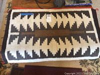 Navajo rug partially folded showing geometric pattern and size tag.