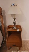 Nightstand with lamp on top showing full setup next to bed and wall