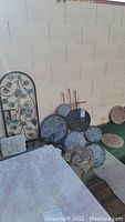 Wide view of collection showing metal grapevine wall panel and various stone plaques arranged against a wall.