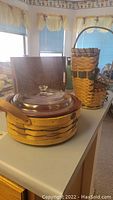 Overview photo showing the round woven basket with clear glass covered dish on swivel base, wooden serving tray behind it, and two half baskets stacked beside it.
