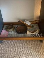 Photo showing the overall lot items on a wooden table: signed wooden roadrunner, two clay pots, and the handmade canoe.