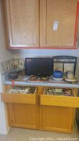 Counter space showing Samsung TV, spice rack, stoneware pots, and decorative wood art pieces.
