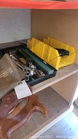 Hand tool lot shelf with a yellow plastic miter box, chisels, and a socket set in black case
