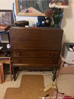 Front view of the antique secretary desk with closed hinged front and two drawers, showing wood grain and knob handles
