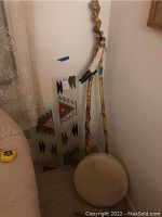 Photo showing rawhide drum, two carved walking sticks, and two stained glass panels with southwest designs.