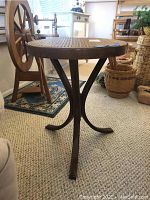 Side view of vintage rattan top table showing curved wooden legs and woven rattan surface