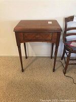Front view of wooden cabinet table consistent with housing a sewing machine inside.