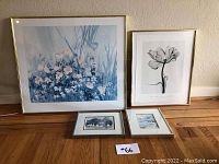 Four framed pieces of artwork arranged against a wall. Large floral print in pastel colors, smaller black and white botanical print, two small duck paintings.