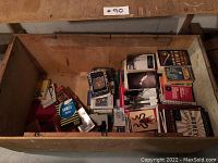 Wooden box filled with assorted books including poetry and other genres, books stacked unevenly and in various conditions.