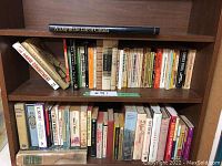 Photo of bookshelf with two rows of assorted books, mostly novels and historical books.