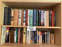 Books on wooden shelves, showing assorted books including travel guides, dictionaries, and novels with visible titles.