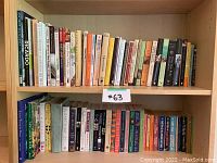 Two shelves of assorted cookbooks and novels, showing spines with various culinary and novel titles.