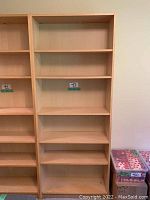 Full view of light wood bookshelf with five shelves and adjacent piece partially visible