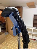 Close-up photo of handheld steam nozzle and hose attached to steamer, showing handle and power cord