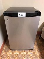 Front view of GE mini fridge showing stainless steel door and black top panel.