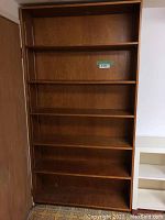 Full view of the large wooden bookshelf showing six shelves and the natural wood grain finish.