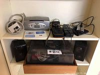Shelf with HP photo scanner, extension cord, two cameras, SanDisk photo card scanner, speakers, and record player covered by transparent dust cover.