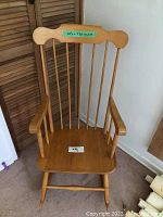 Full view of the wooden rocking chair showing the spindle backrest and armrests.