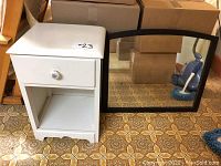 Photo of white side table and black framed wall mirror side by side