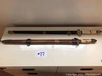 Full-length overview of both swords on flat surface