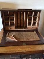 Open antique writing desk top showing cubby compartments, vertical file slots, small drawers, and worn writing surface.