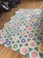 Top-down view of quilt laid on floor showing full pattern and overall shape with scalloped edge