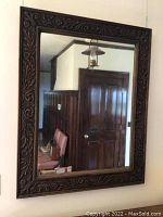 Full view of the large rectangular mirror mounted on wall, showing wood frame and reflected room.