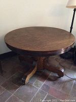 Full view of round quarter sawn oak tabletop and pedestal base with curved legs.