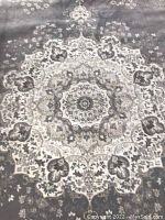 Close-up of the rug's central medallion pattern in pale grey and cream.