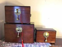 Three rectangular wooden nesting boxes stacked, reddish wood, brass fish padlocks visible.