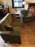 Couch and armchair overview showing velvet upholstery and carved wooden trim, with two throw pillows on couch