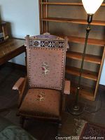 Victorian wooden swivel rocker chair with mauve needlepoint floral upholstery, shown with armrests and carved wood details.