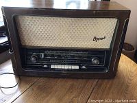 Front view of wooden-cased radio with speaker grille and tuning dial