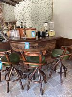 L-shaped wooden bar with four green cushioned swivel bar stools arranged around it, showing condition and structure.