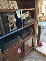 Shelf with vintage audio and video equipment including cassette deck, CD player, turntable, receiver, and VHS player