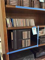 Full shelf view showing CDs lined up and black CD storage binder next to audio equipment.